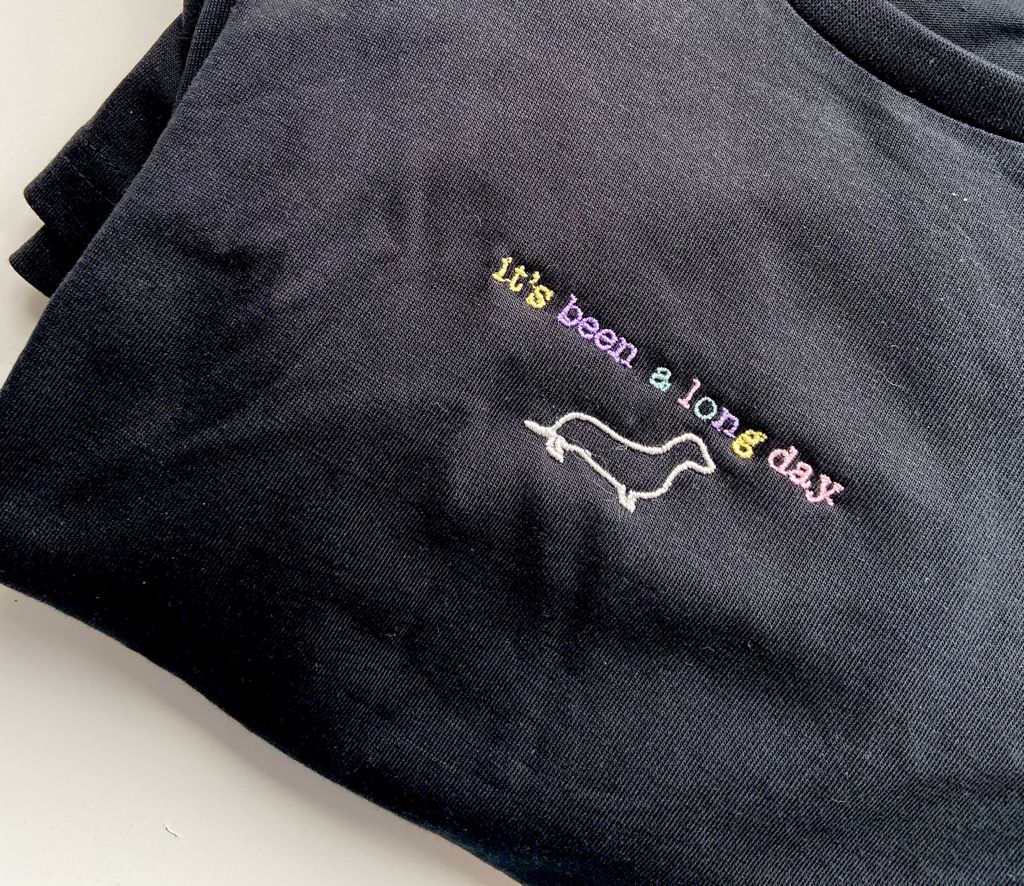 Black t-shirt with colorful embroidered text 'it's been a long day' and dachshund outline, Ineedledit personalized pet embroidery gift