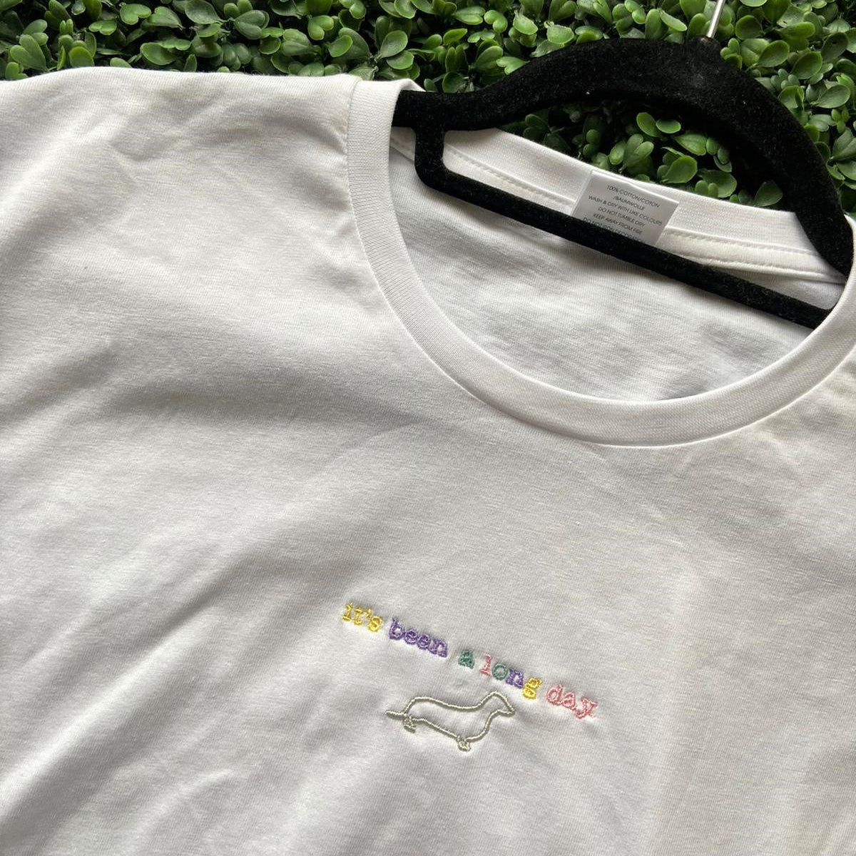 White t-shirt with colorful embroidered text 'it’s been a long day' and dachshund outline, Ineedledit.